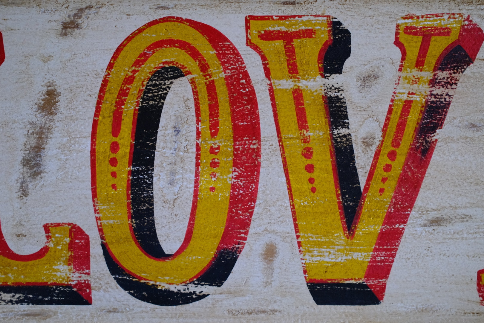 Close-up of a distressed 'LOVE' sign with yellow and red letters on a textured background.
