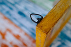 Close-up of a yellow frame corner with a black clip on a colorful background
