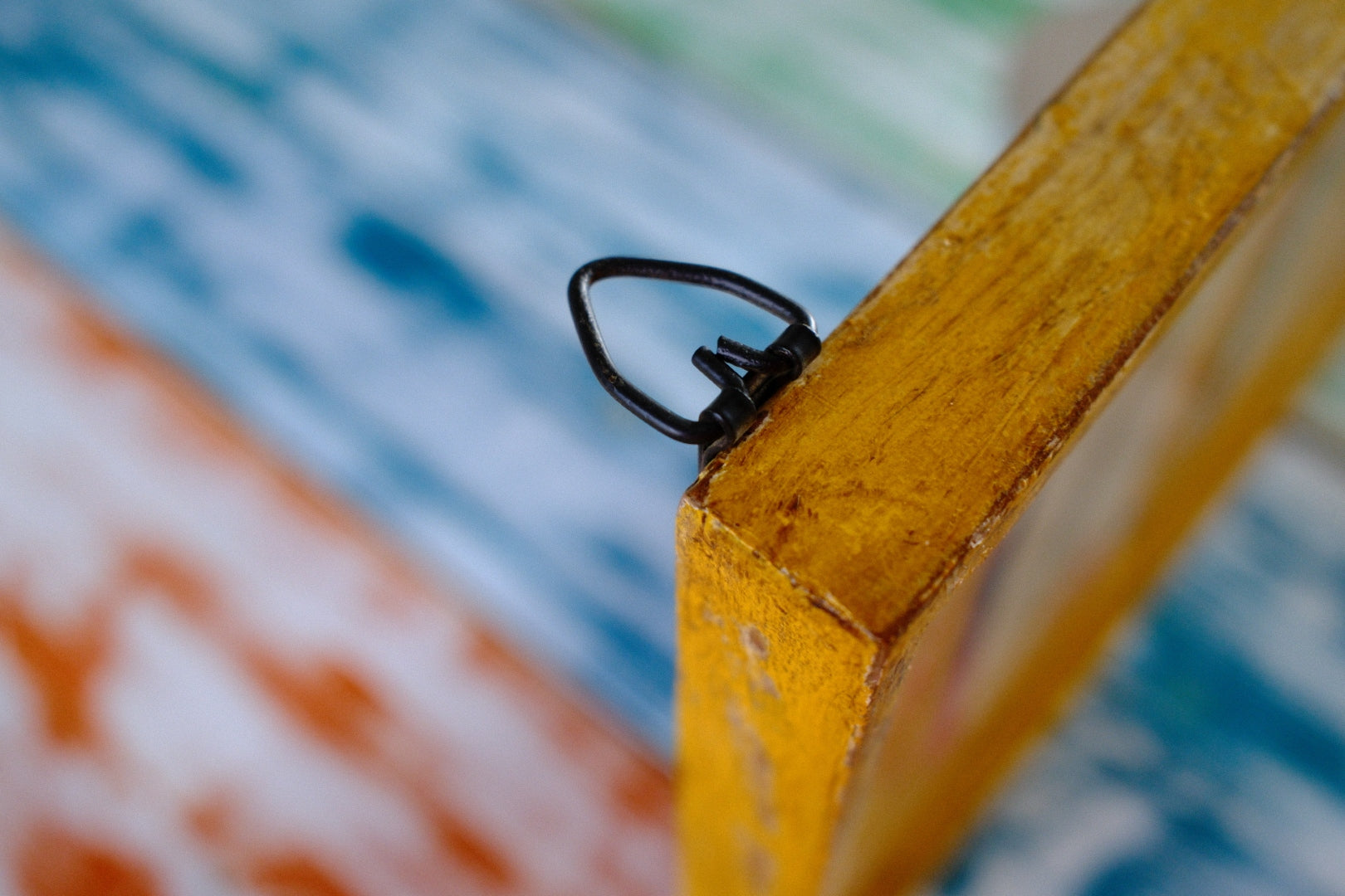 Close-up of a yellow frame corner with a black clip on a colorful background