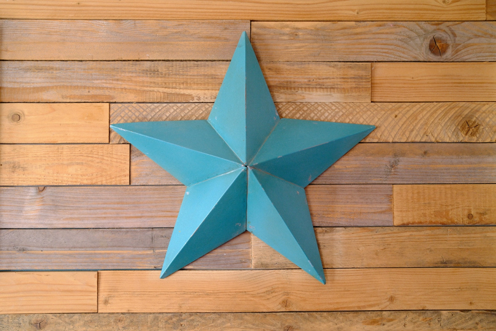 Blue metal barn star-shaped decorative item on a wooden wall