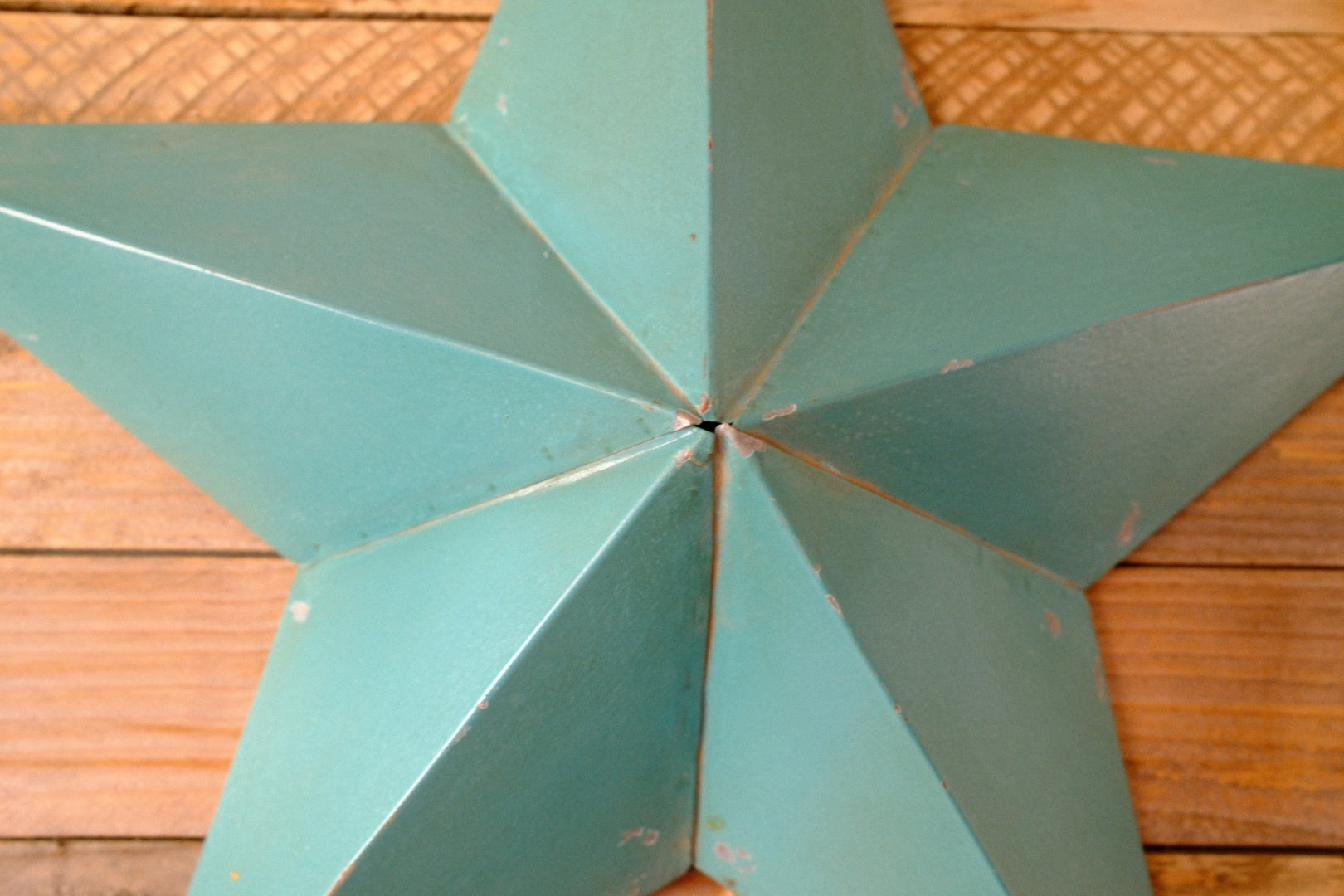 Teal metal rustic barn star against a wooden background
