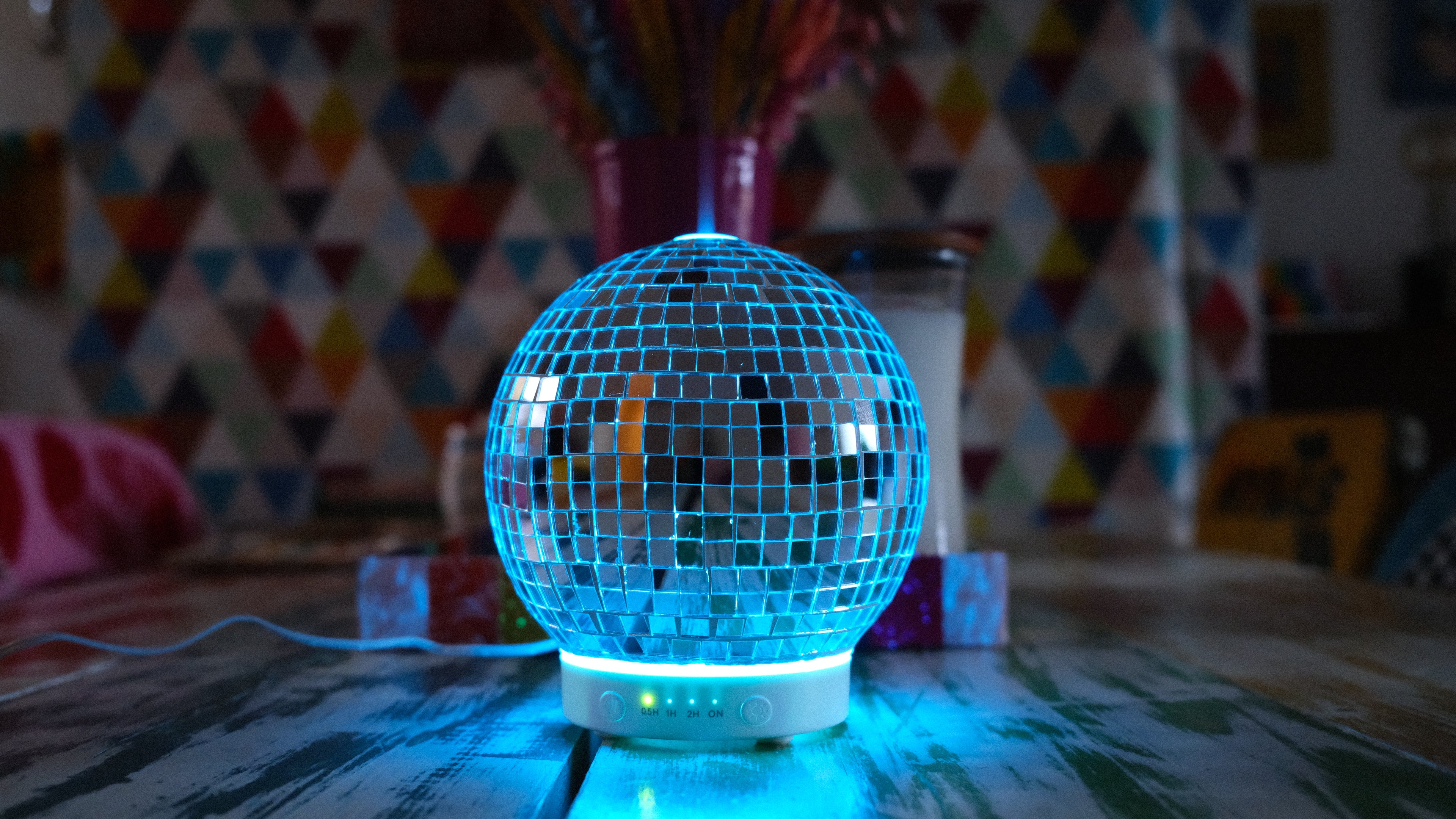 Discoball diffuser on a table with a colorful geometric patterned wall in the background
