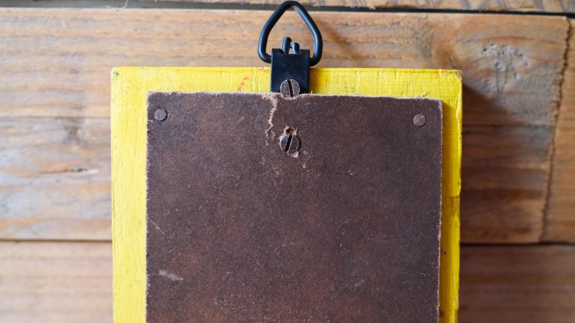 Yellow card holder with a brown leather patch on a wooden surface