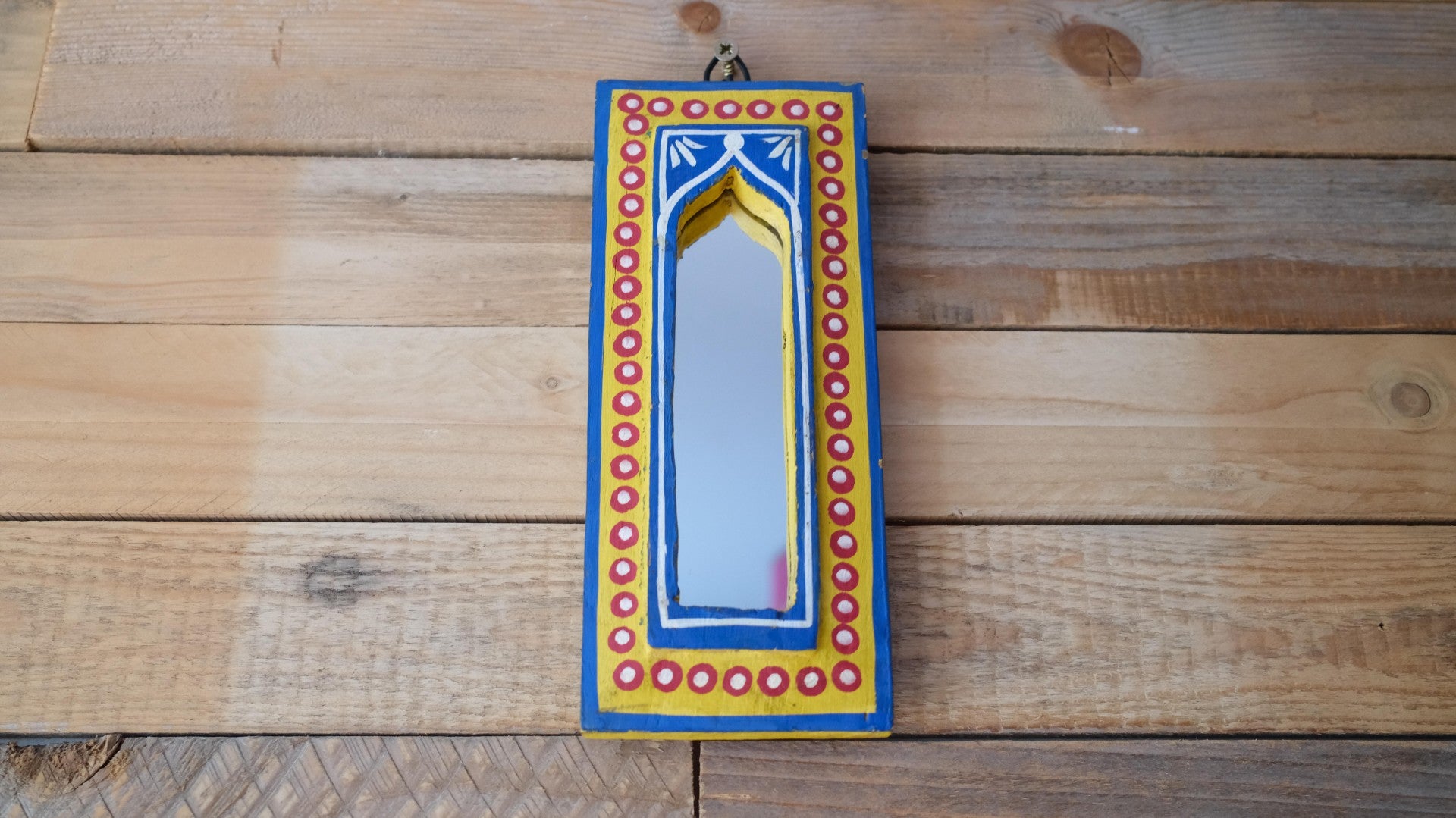 Decorative mirror with colorful frame on a wooden surface