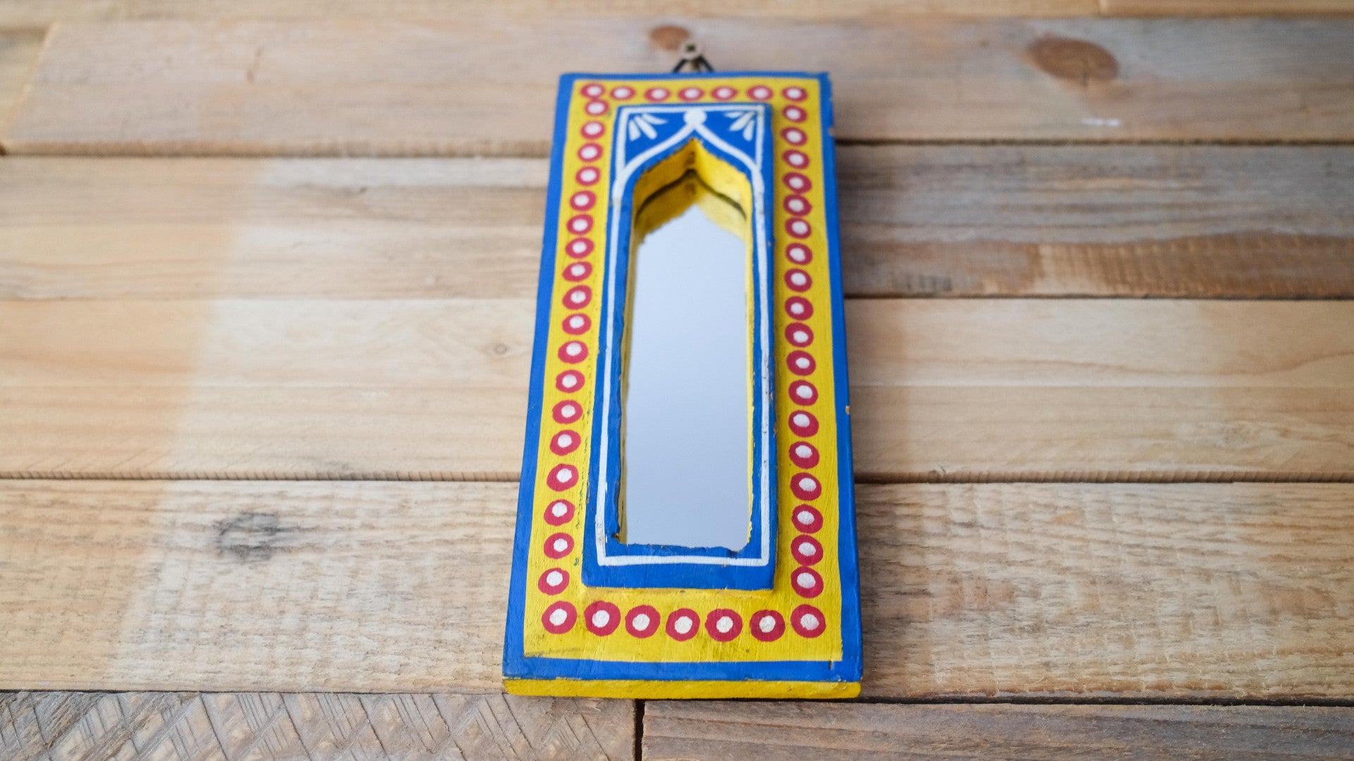 Decorative mirror with colorful frame on a wooden surface