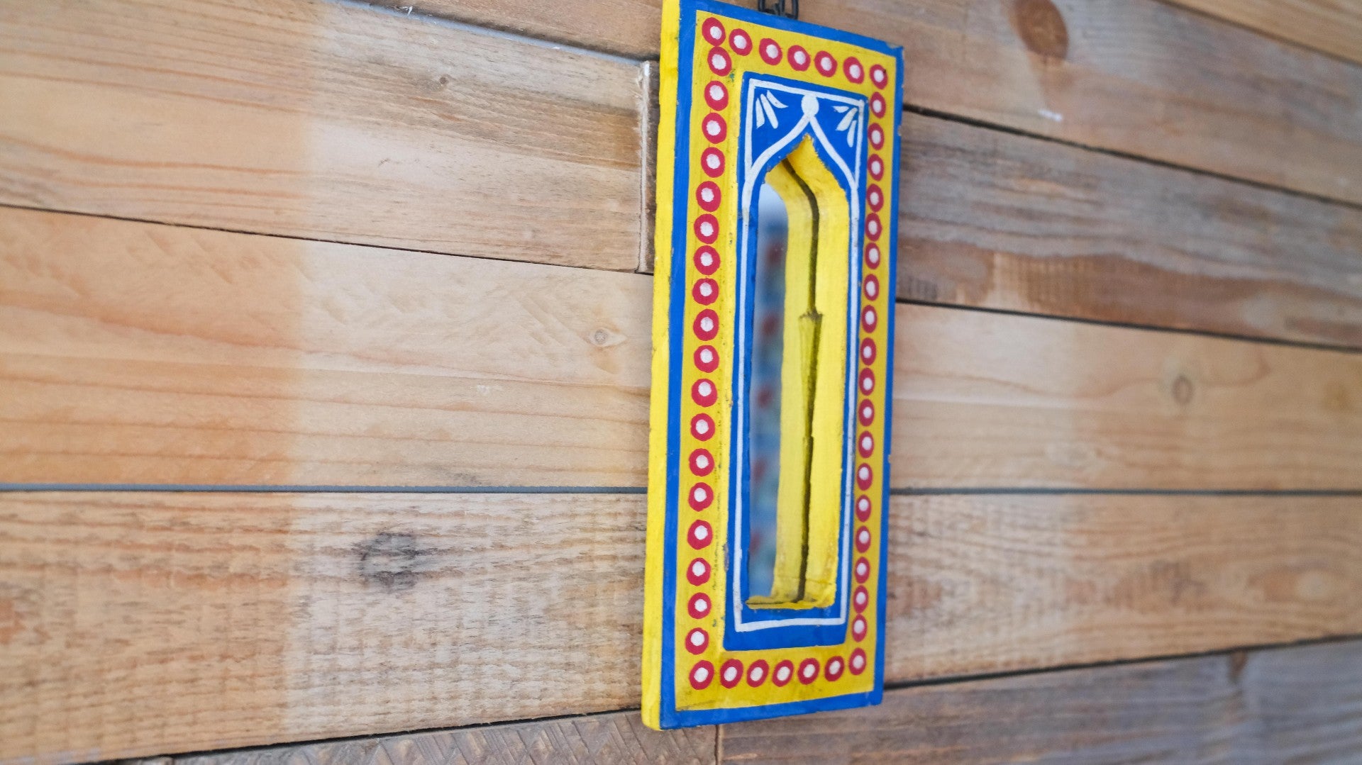Decorative yellow object with a blue and red frame on a wooden surface
