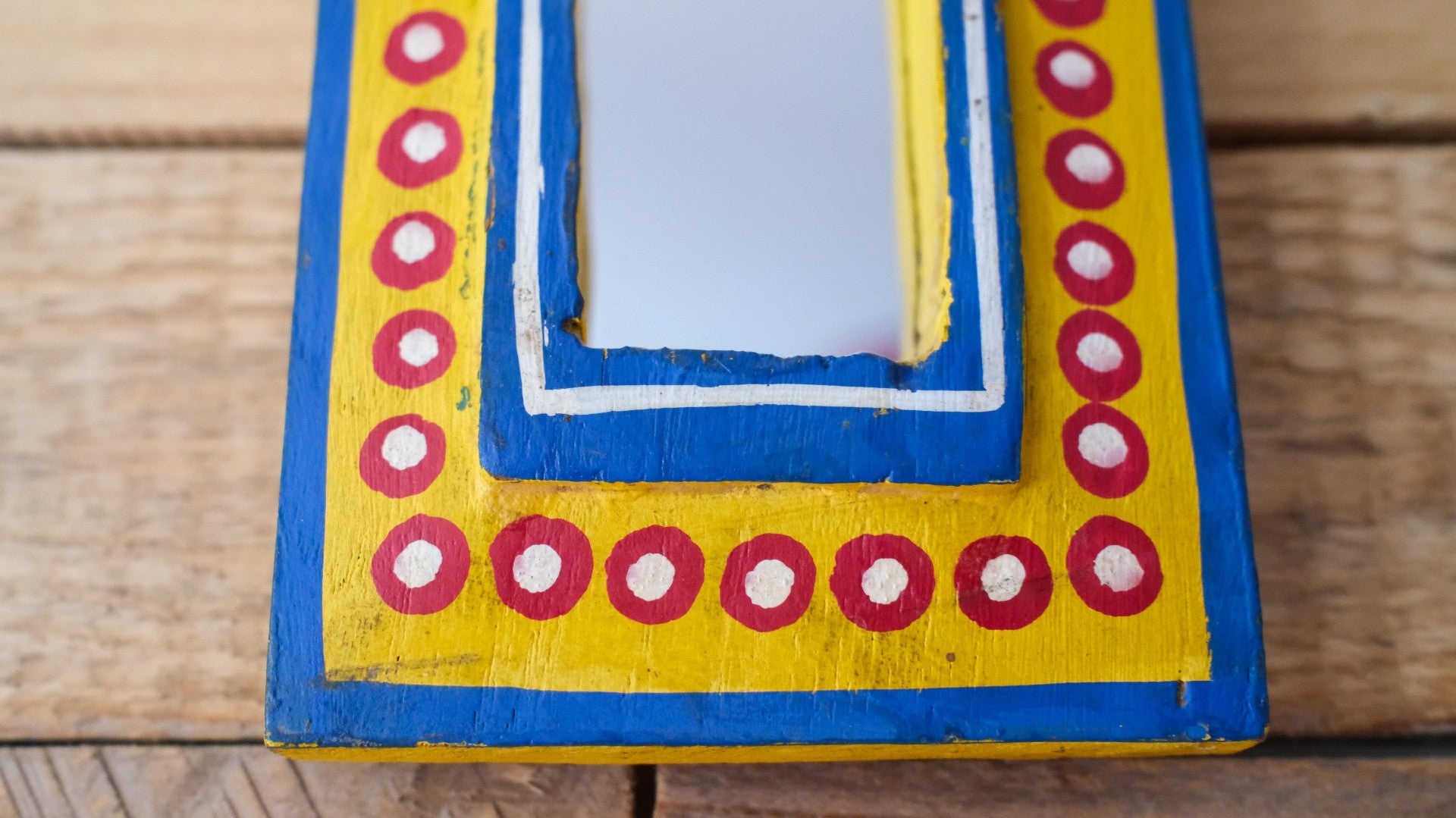 Decorative mirror with a colorful frame on a wooden surface