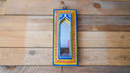 Decorative mirror with a colorful frame on a wooden wall