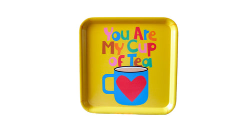 Yellow tray with colorful text and a heart-shaped mug graphic on a floral fabric background.