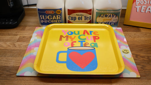 Yellow tray with 'You Are My Cup of Tea' design on a wooden surface with tea products in the background.