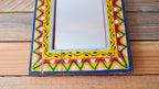 Decorative mirror with a colorful geometric frame on a wooden surface
