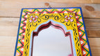 Decorative mirror with colorful frame on a wooden surface