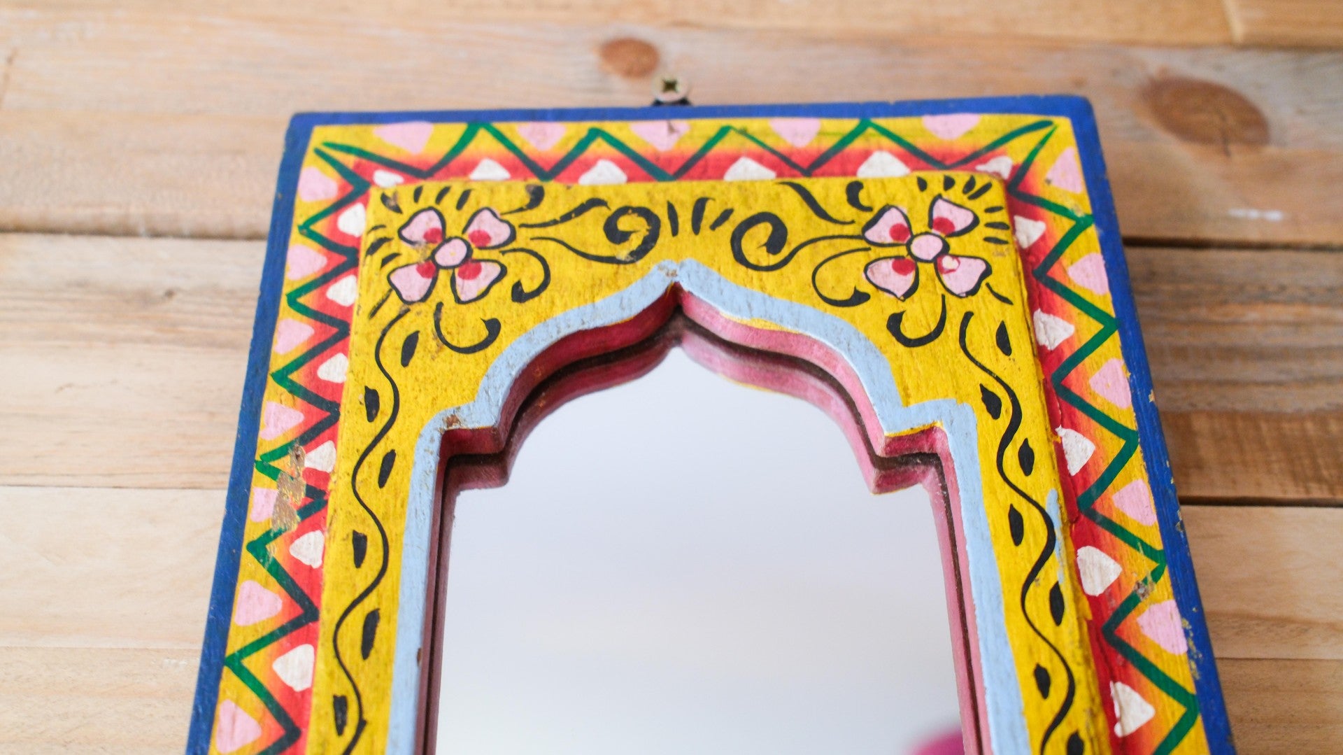 Decorative mirror with colorful frame on a wooden surface