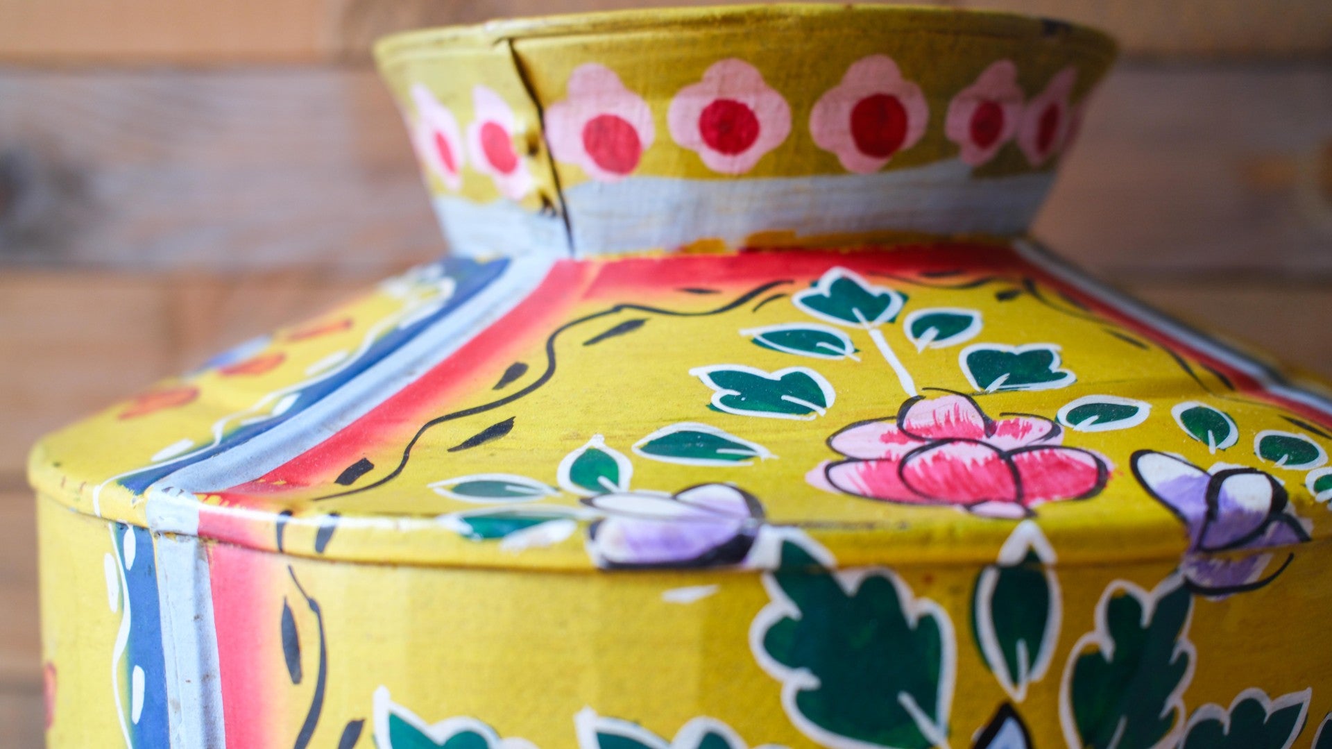 Colorful metal pot with floral patterns on a wooden surface