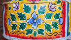 Colorful tin with floral patterns on a yellow background