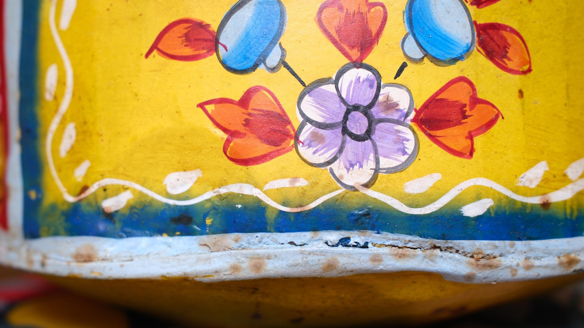 Close-up of a colorful painted object with floral designs on a yellow background