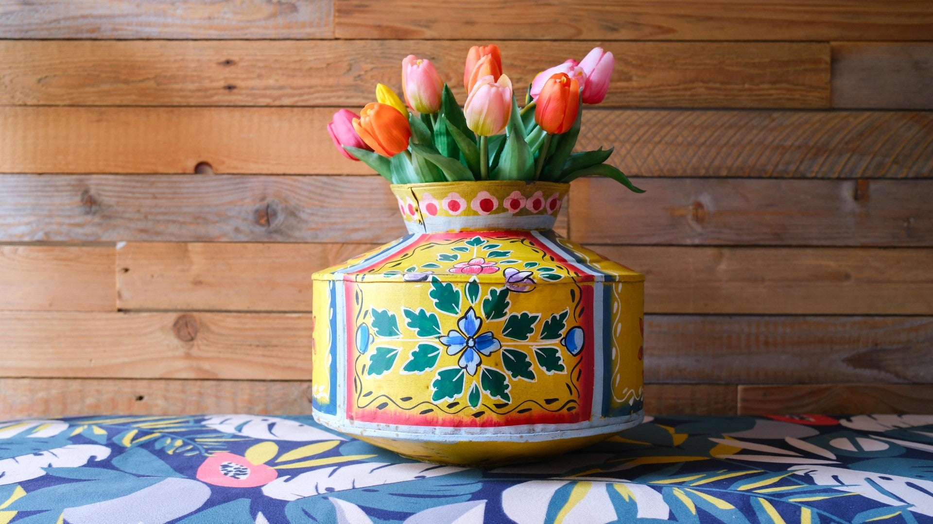 Decorative box with colorful floral design and tulips on a wooden background