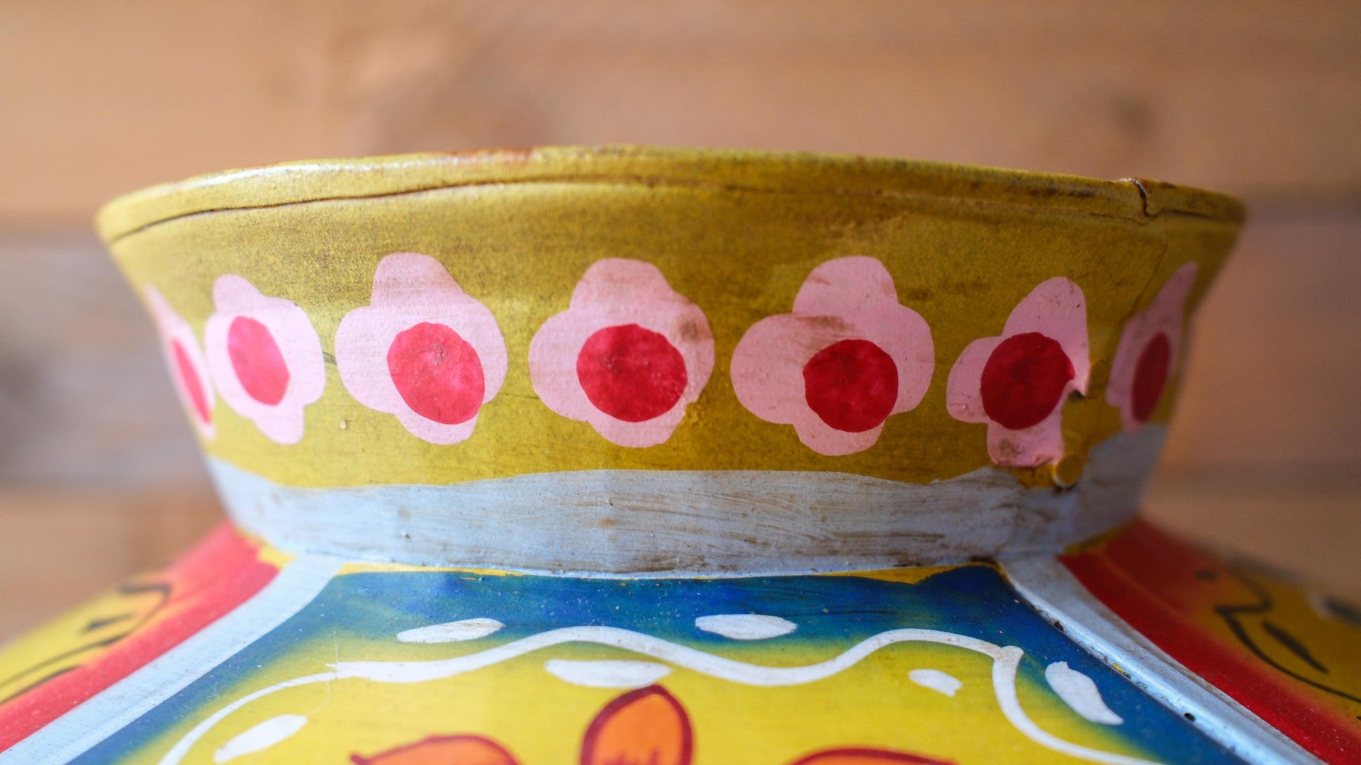 Colorful metal pot with floral patterns on a wooden surface