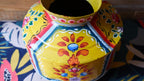 Colorful decorative pot with floral patterns on a patterned surface