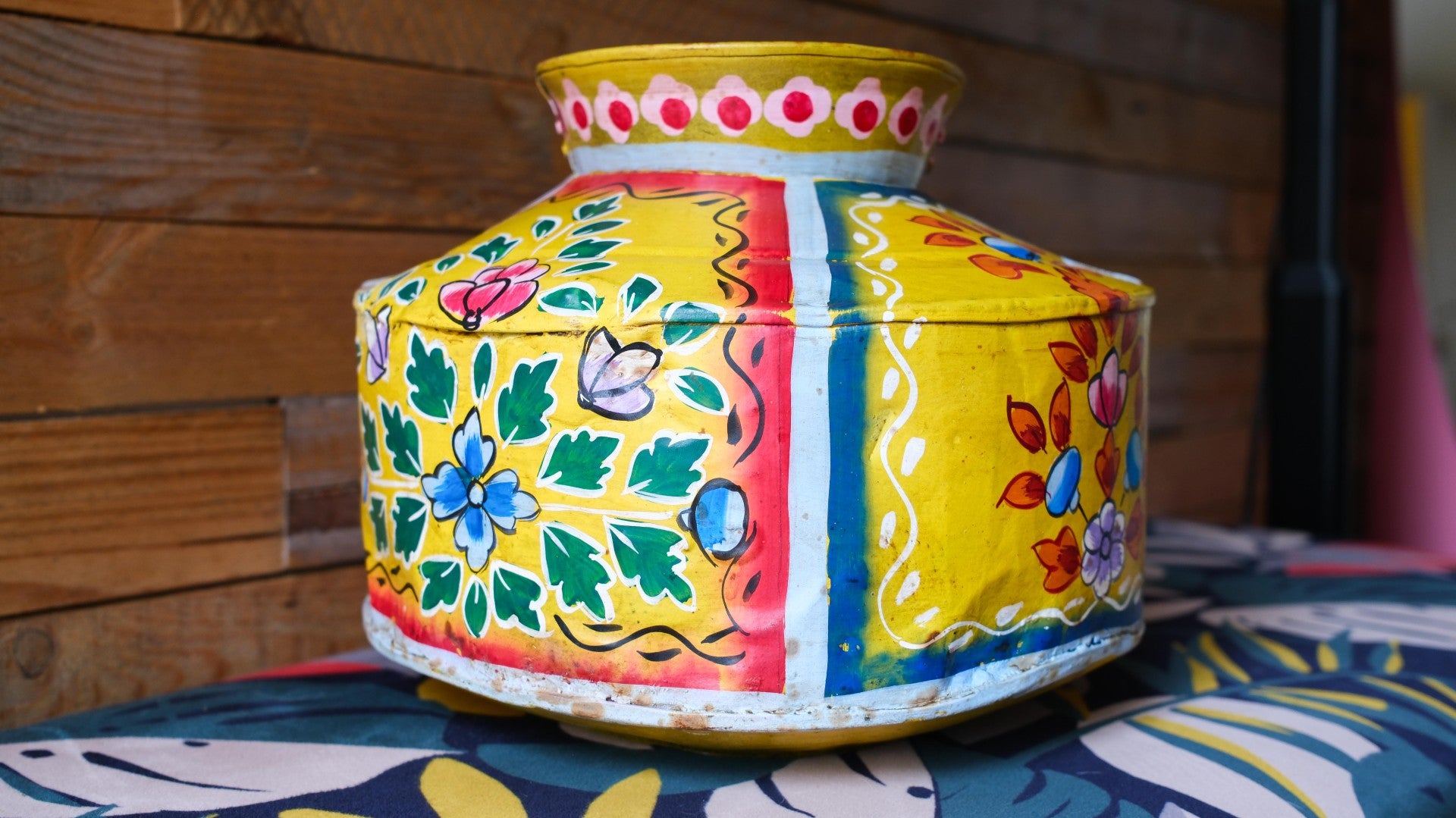 Colorful hand-painted container with floral designs on a wooden surface